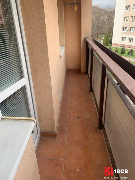 Balkon einer 2-Zimmer-Wohnung mit Terrakottafliesen und Blick ins Grüne.