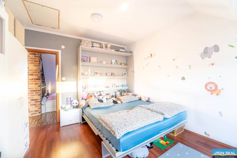 Kinderzimmer in einer Zweizimmerwohnung mit Bett, Regalen und Boden in Holzoptik.