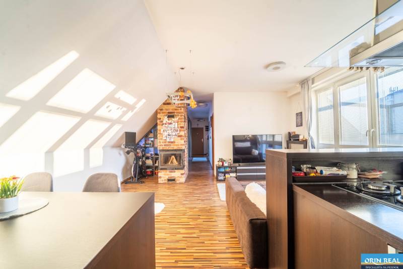 Wohnzimmer in einer 2-Zimmer-Wohnung mit Holzboden und gemauertem Kamin.