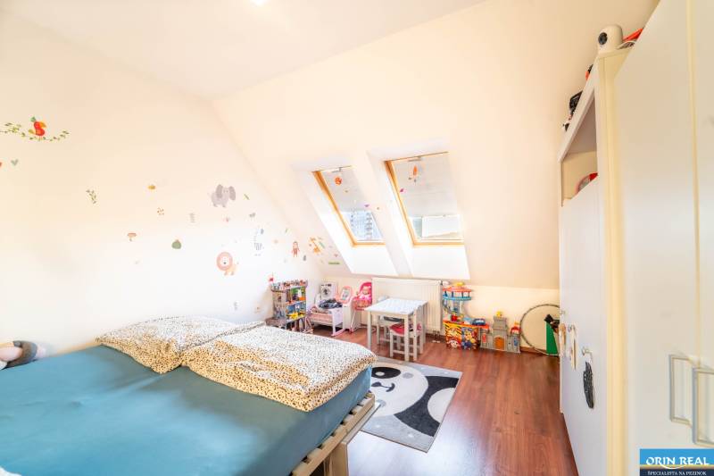 Kinderzimmer in einer 2-Zimmer-Wohnung mit Dachfenstern, Möbeln und Spielzeug.