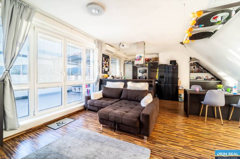 Wohnzimmer mit bequemer Couch, Holzboden und großen Fenstern in einer 2-Zimmer-Wohnung.