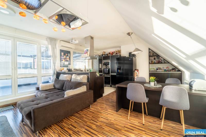 Wohnzimmer mit Küche in einer 2-Zimmer-Wohnung mit Holzboden und bequemer Couch.