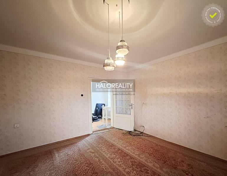 Ein Zimmer in einem Einfamilienhaus mit Teppichboden und Hängelampe.