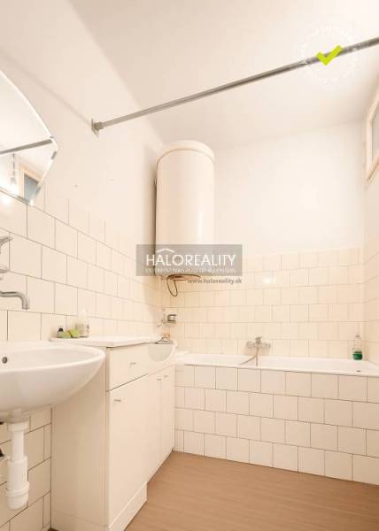 Badezimmer im Einfamilienhaus mit Badewanne, Waschbecken und Boden mit Holzdekor.