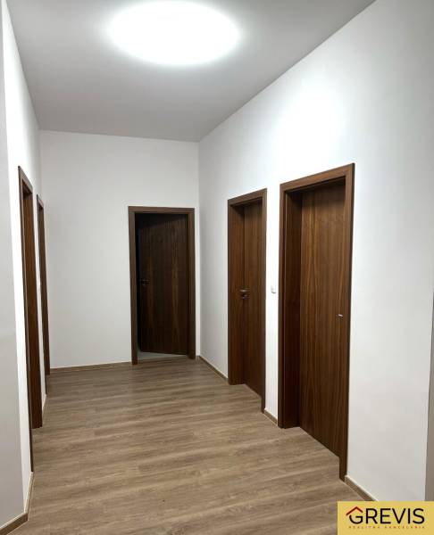 Ein Flur mit einem Boden in Holzdekor in einer 4-Zimmer-Wohnung und Türen in Holzoptik.