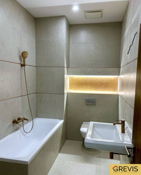 Badezimmer mit Badewanne, Duschkopf, WC und Beleuchtung in einer 4-Zimmer-Wohnung.