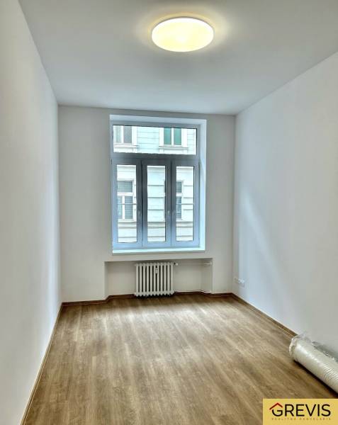 Ein Zimmer mit hellen Wänden und einem Boden in Holzoptik in einer 4-Zimmer-Wohnung.