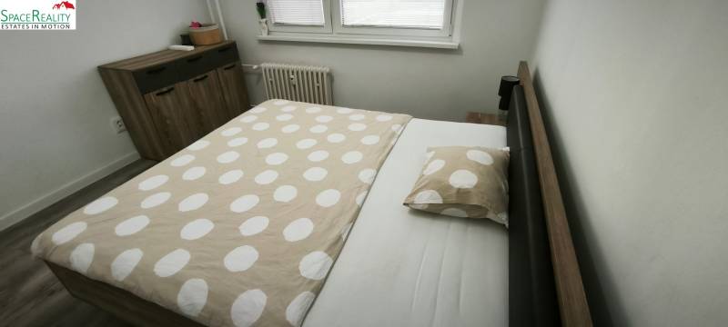 Schlafzimmer in einer 3-Zimmer-Wohnung mit Bett, Kommode und Boden mit Holzdekor.