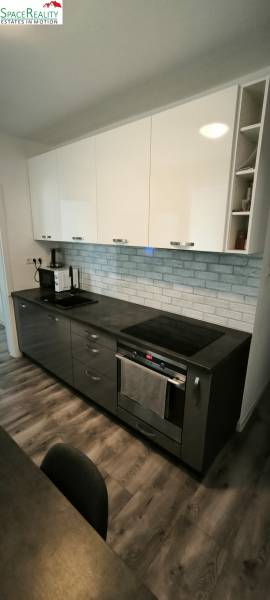 Küche in einer 3-Zimmer-Wohnung mit dunklen Schränken und einem Boden in Holzoptik.