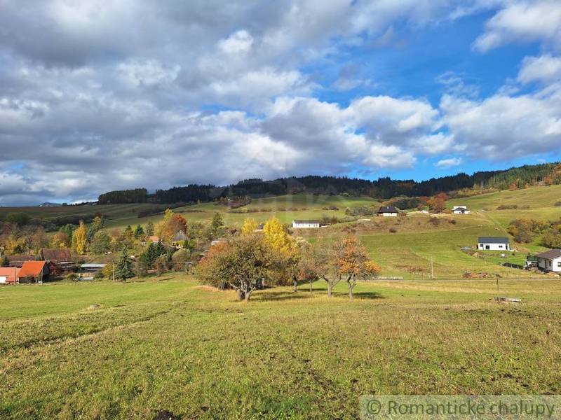 Herbst in Liptovské Beharovce mit verstreuten Einfamilienhäusern auf grünen Hügeln unter einem bewölkten Himmel.