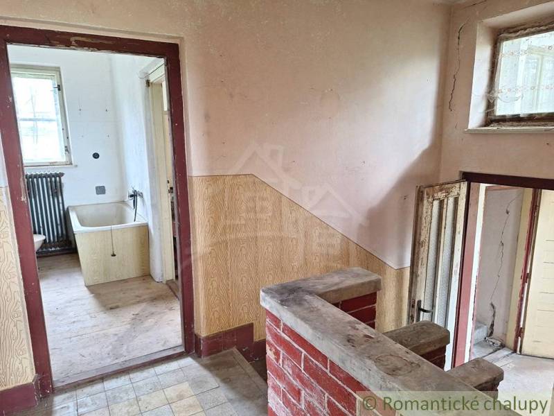 Innenraum eines Einfamilienhauses mit Verkleidung, alter Badewanne und Boden mit Holzdekor.