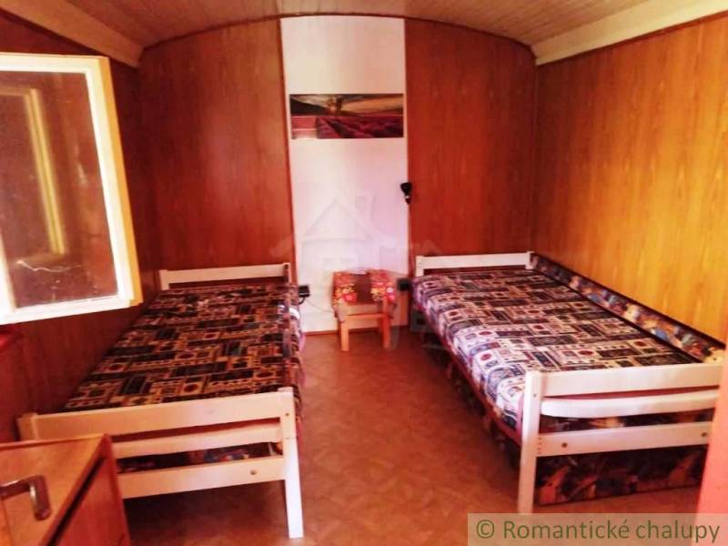 Innenraum einer Holzhütte mit zwei Betten und einem Boden in Holzoptik.