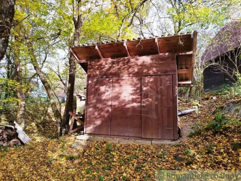 Eine kleine Holzhütte im Wald bei Dudince, umgeben von Herbstblättern.