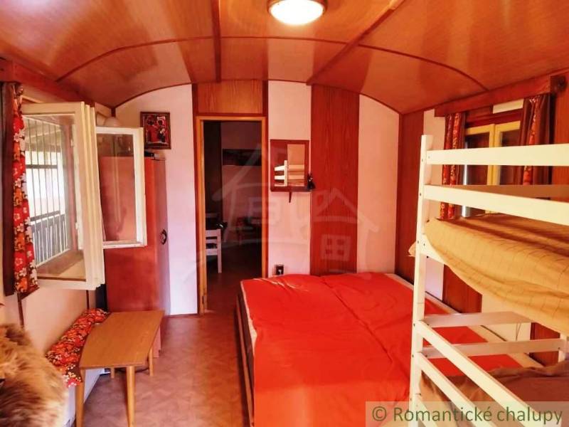 Das Innere einer Hütte mit einem Etagenbett, einem Boden in Holzoptik und einem offenen Fenster.