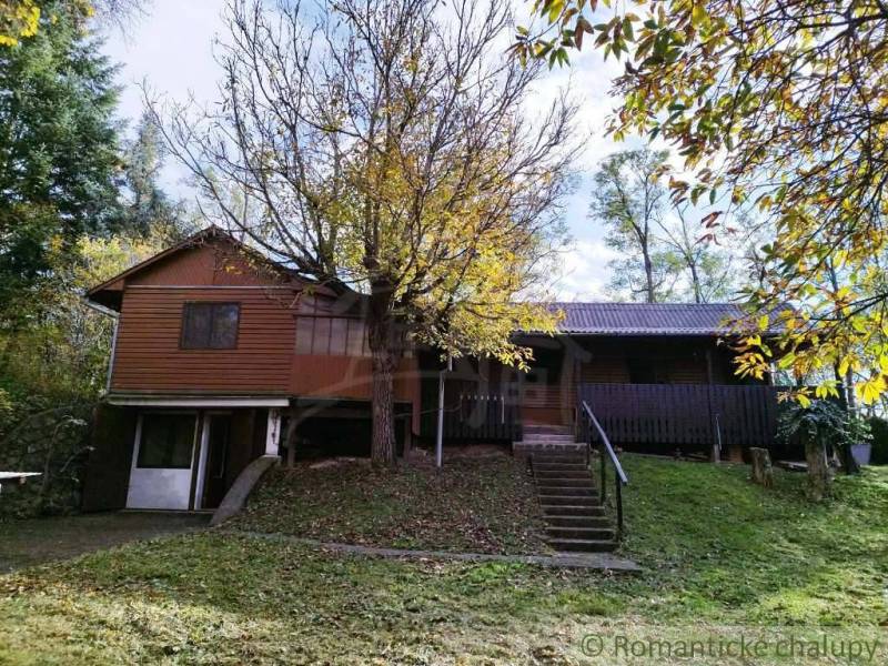 Ein Ferienhaus in Dudince, umgeben von Bäumen und üppigem Grün, ideal zum Entspannen.