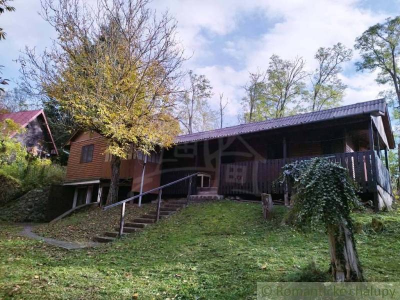 Ein Ferienhaus in Dudince, umgeben von Natur, mit Terrasse und Bäumen im Garten.