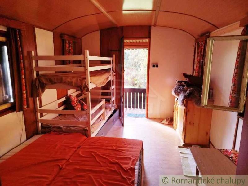 Innenraum einer Hütte mit vier Betten und einem hellen Ausblick auf die Terrasse.