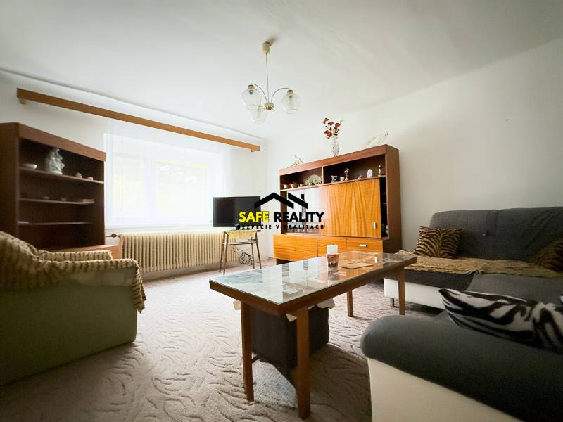 Wohnzimmer in einem Einfamilienhaus mit Sofas, Schränken und einem Tisch, Teppich auf dem Boden.