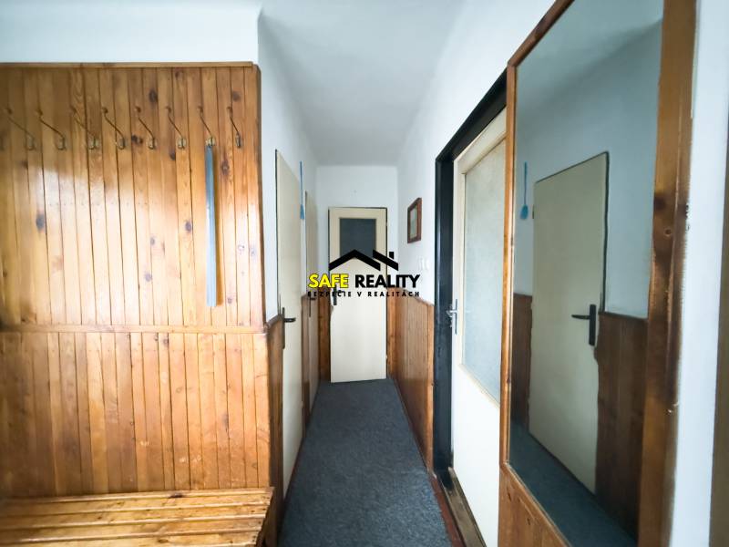 Eingangsflur in einem Einfamilienhaus mit Holzverkleidung und einem Spiegel an der Wand.