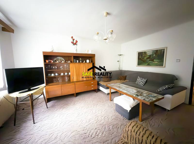 Wohnzimmer in einem Einfamilienhaus mit Sofa, Fernseher und Holzwohnwand.