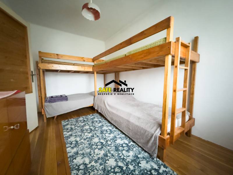 Etagenbett in einem Einfamilienhaus mit Holzboden und gemustertem Teppich.