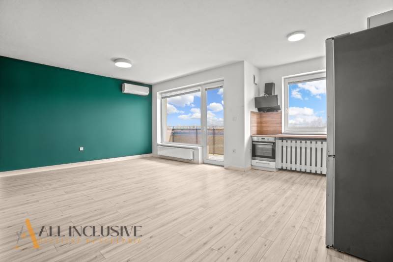 Wohnzimmer mit Küchenzeile in einer 2-Zimmer-Wohnung und einem Bodenbelag in Holzoptik.