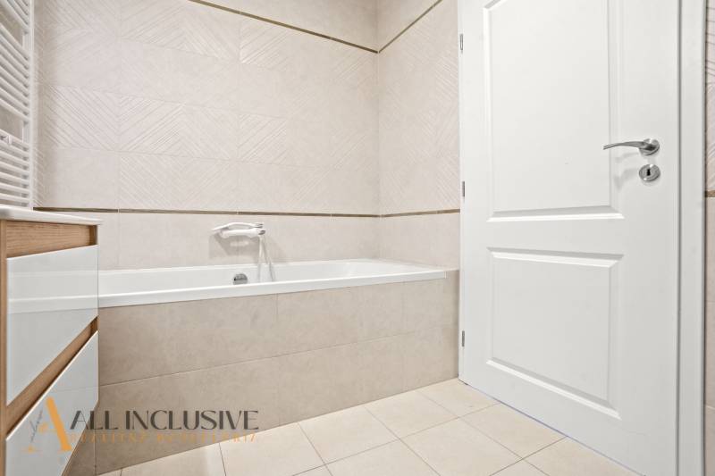 Badezimmer mit Badewanne, weißen Türen und hellen Fliesen in einer 2-Zimmer-Wohnung.