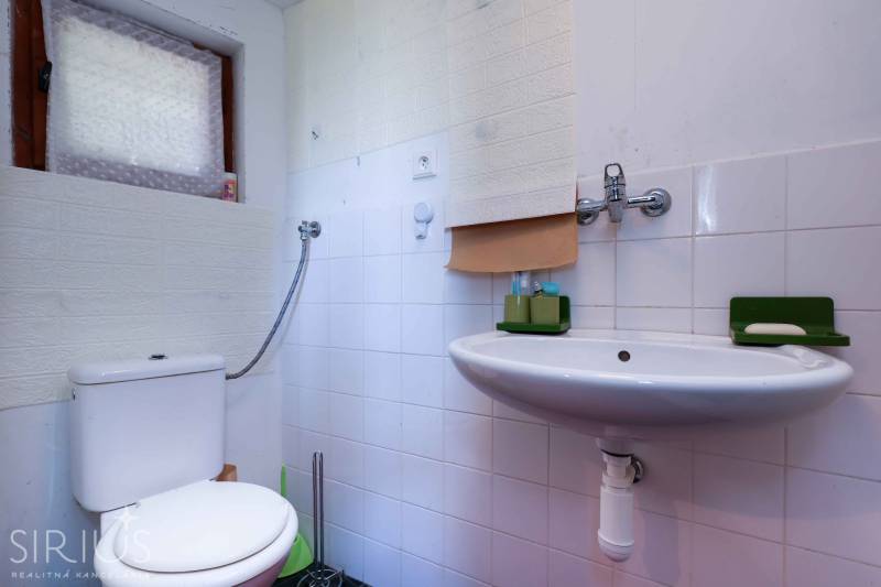 Badezimmer mit Dusche und Waschbecken, Gärten. Weiße Fliesen und grüne Accessoires.