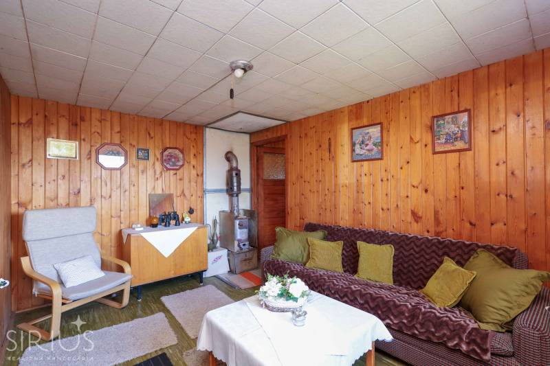 Ein Zimmer mit Sofa, Sessel, Tisch und Holzvertäfelung bietet einen gemütlichen Raum in den Gärten.