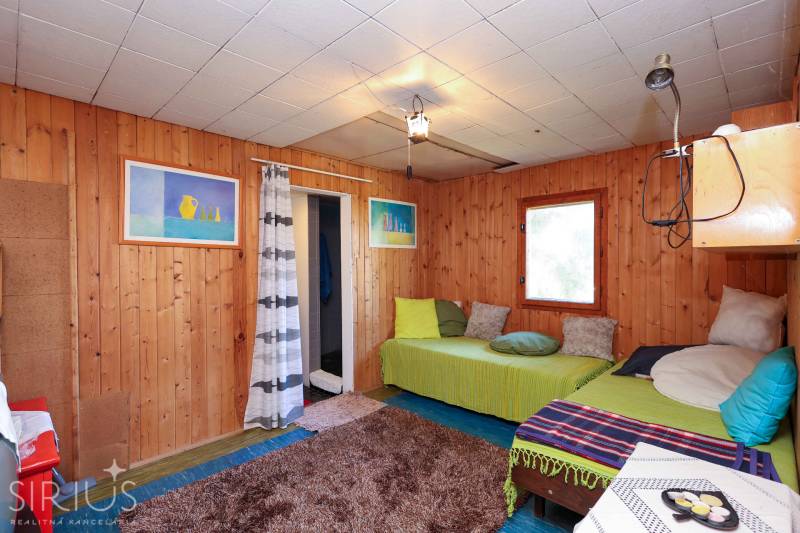 Holzverkleidung an den Wänden, Sofas mit Kissen und Teppich im Inneren der Gartenhütte.