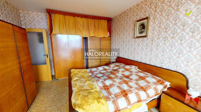 Schlafzimmer in einer 3-Zimmer-Wohnung mit dekorativer Tapete und Holzmöbeln.