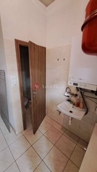 Badezimmer in Geschäftsräumen mit Waschbecken, Boiler und Tür zur Toilette.