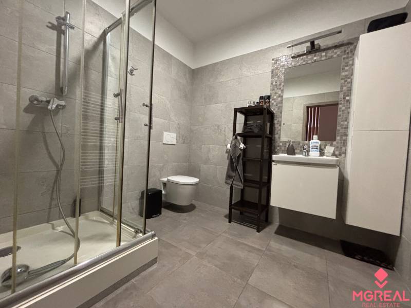 Badezimmer einer Zweizimmerwohnung mit moderner Duschkabine und Platz für Hygieneartikel.