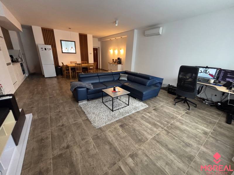 Wohnzimmer in einer Zweizimmerwohnung mit einem blauen Sofa und einem Schreibtisch.