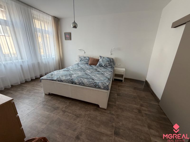 Schlafzimmer in einer 2-Zimmer-Wohnung mit einem großen Bett und einem Fliesenboden.