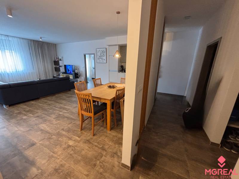 Esstisch mit Holzstühlen in einer 2-Zimmer-Wohnung. Dazu gehören ein Sofa und ein Fernseher.