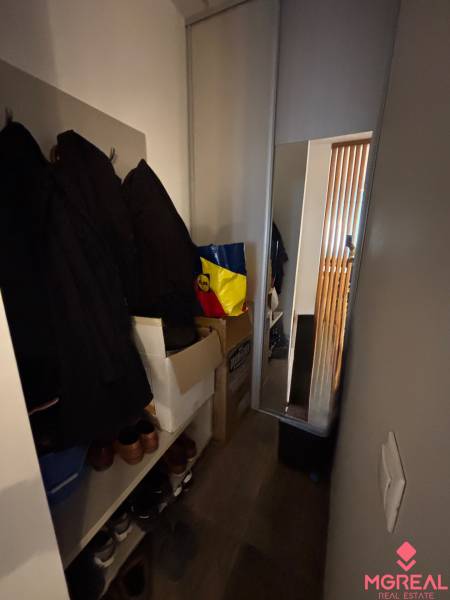 Ein enger Raum in einer 2-Zimmer-Wohnung mit Kleiderhaken, Kleiderschrank und Spiegel.