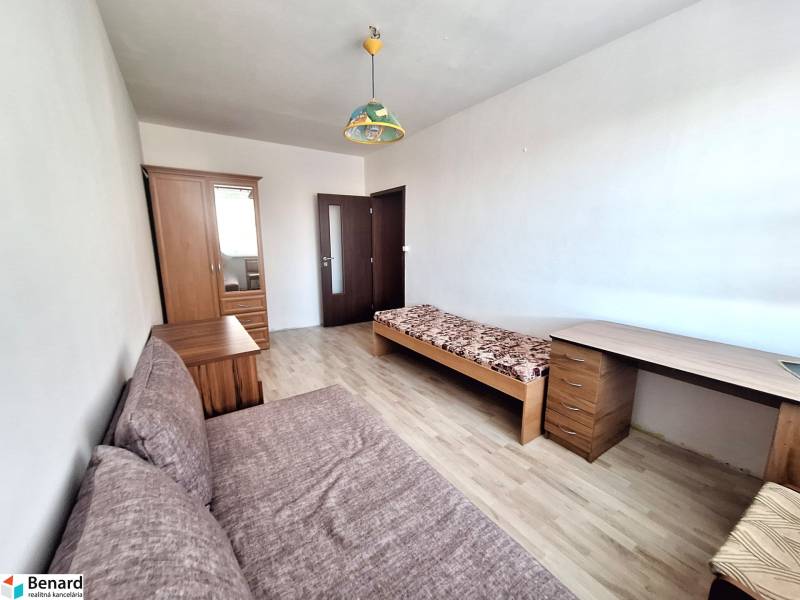 Ein Zimmer in einer 3-Zimmer-Wohnung mit einem Holzboden, einem Bett und einem Schrank.