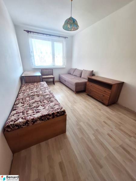 Ein Zimmer in einer 3-Zimmer-Wohnung mit einem Boden in Holzoptik, einem Sessel und einem Bett.