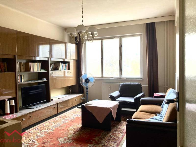 Wohnzimmer in einer 3-Zimmer-Wohnung mit Möbeln, Teppich und großem Fenster.