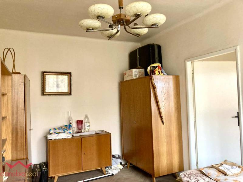 Ein Zimmer in einer 3-Zimmer-Wohnung mit Holzmöbeln und einem dekorativen Kronleuchter.