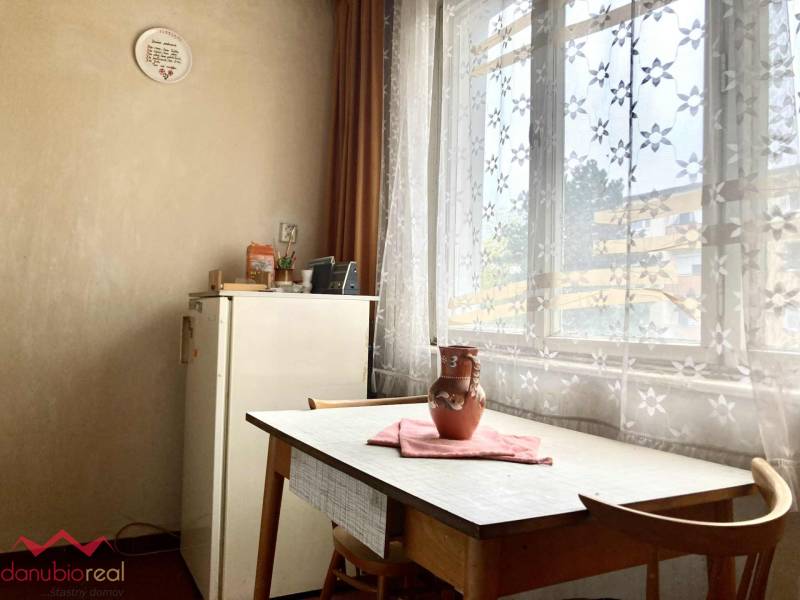 Esszimmer in einer 3-Zimmer-Wohnung mit Tisch, Stühlen und Vorhängen mit Blumenmuster.