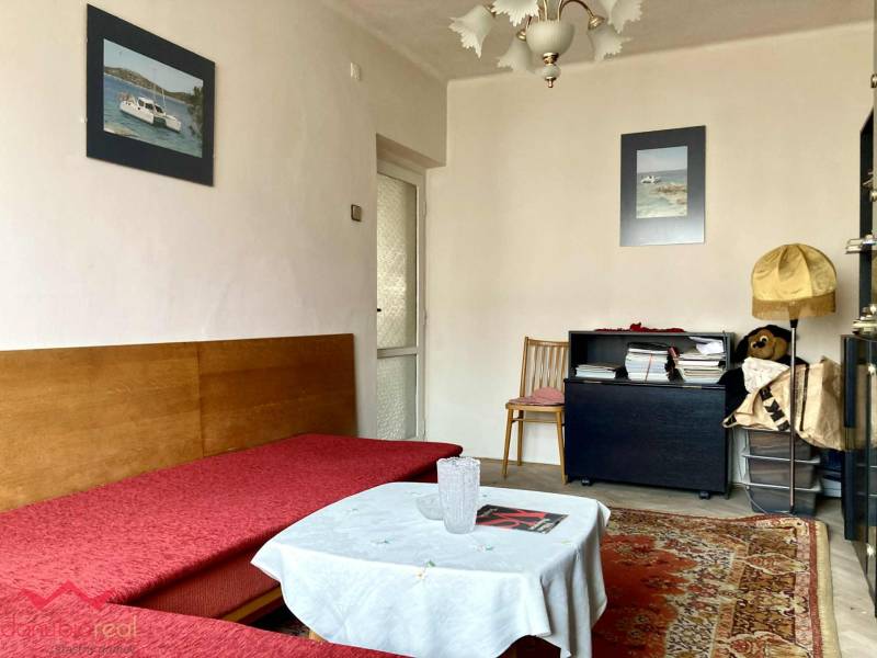 Wohnzimmer in einer 3-Zimmer-Wohnung mit Sofa, Teppich und dekorativen Bildern an der Wand.