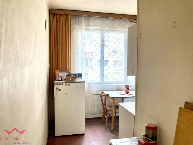 Küche in einer 3-Zimmer-Wohnung mit Holzboden, einfacher Einrichtung und Fenster.