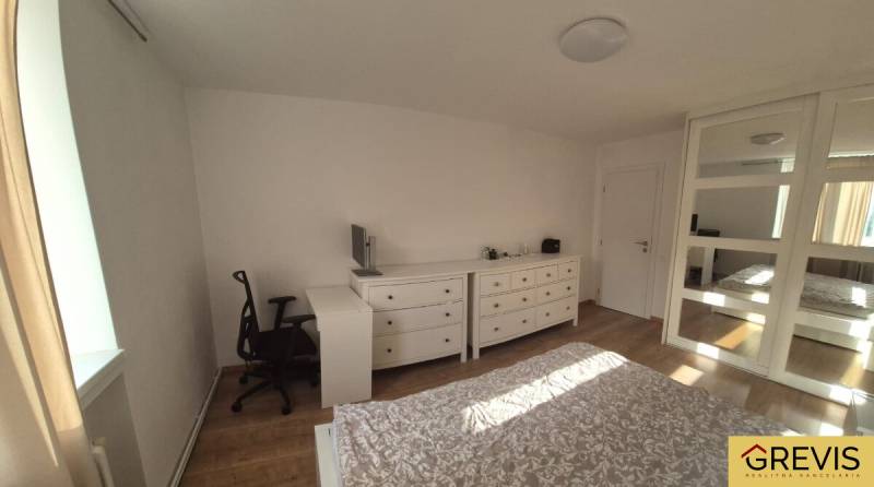 Schlafzimmer in einer 3-Zimmer-Wohnung mit Holzboden, Einbauschrank und Schreibtisch.
