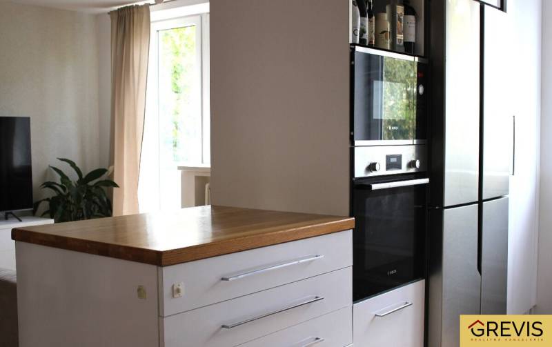 Küche in einer 3-Zimmer-Wohnung, dunkler Schrank mit eingebautem Ofen, daneben ein Kühlschrank.