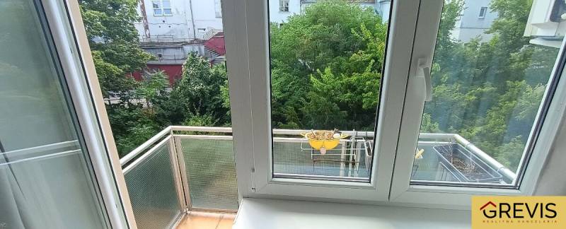 Blick aus einer 3-Zimmer-Wohnung mit Fenstern und Balkon in einen grünen Innenhof.