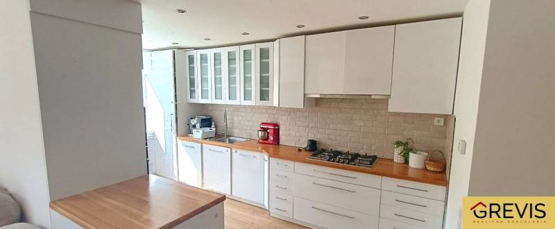 Küche in einer 3-Zimmer-Wohnung mit weißen Möbeln und Herd, Boden mit Holzdekor.