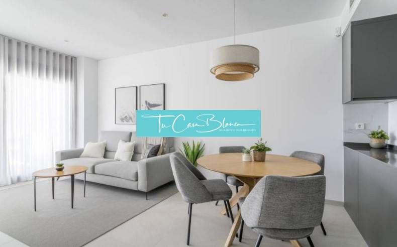 Helles Wohnzimmer der Ferienwohnung mit grauem Sessel und Holztisch.