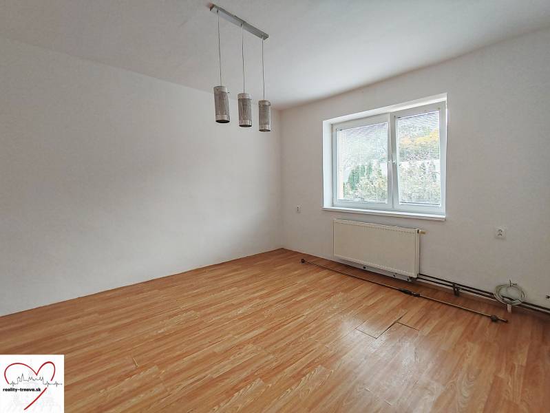 Ein Zimmer in einem Einfamilienhaus mit einem Holzboden und einem großen Fenster.